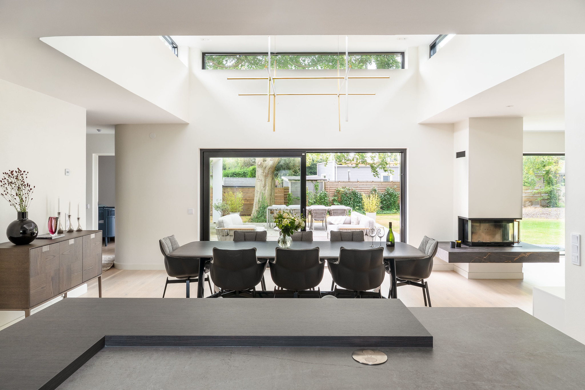 Fantastisk vy från köket i ett dast stenhus mot en ljus matplats med lanternin och stort glasskjutparti