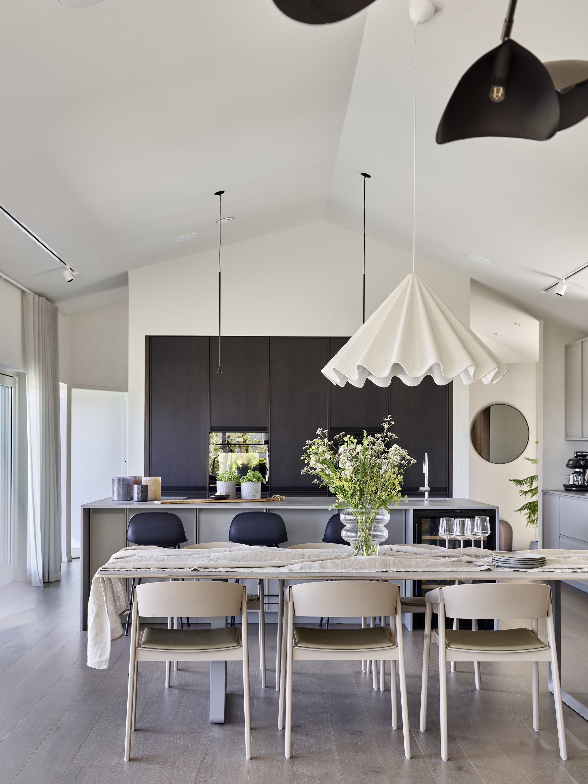 Rymligt kök och matplats med ryggåstak i modernt två-planshus byggt av dast stenhus