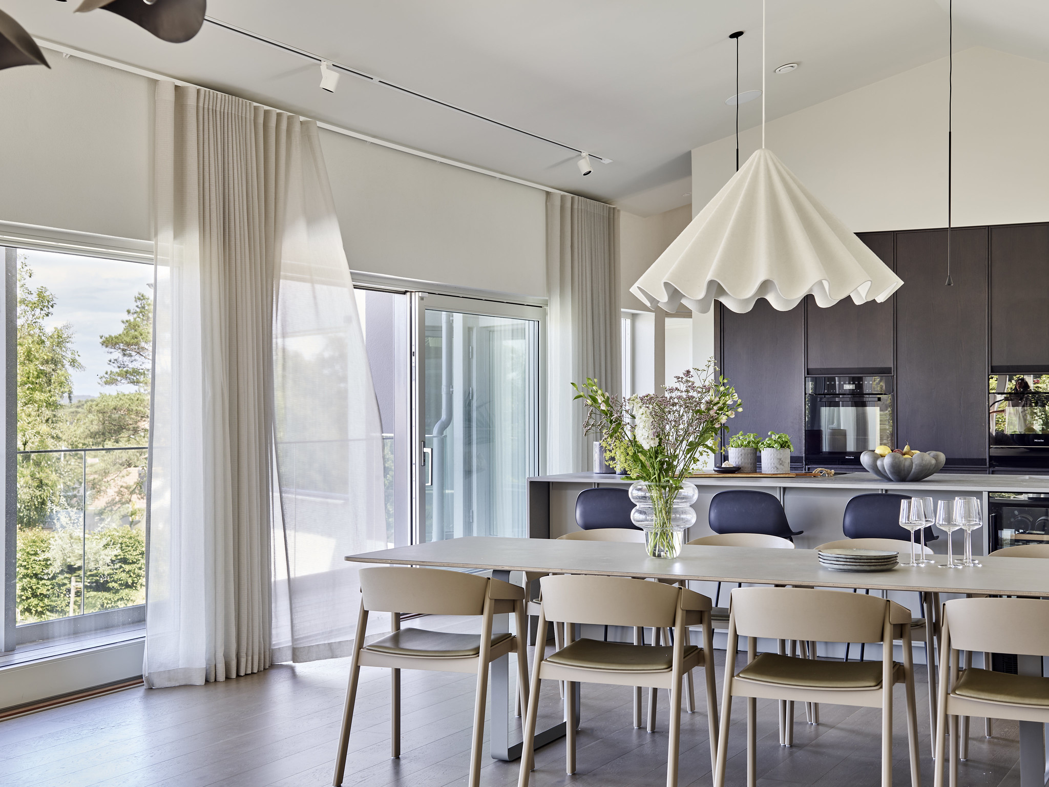 Dast stenhus med stora glaspartiet vid kök och matplats i direkt kontakt med uteplatsen