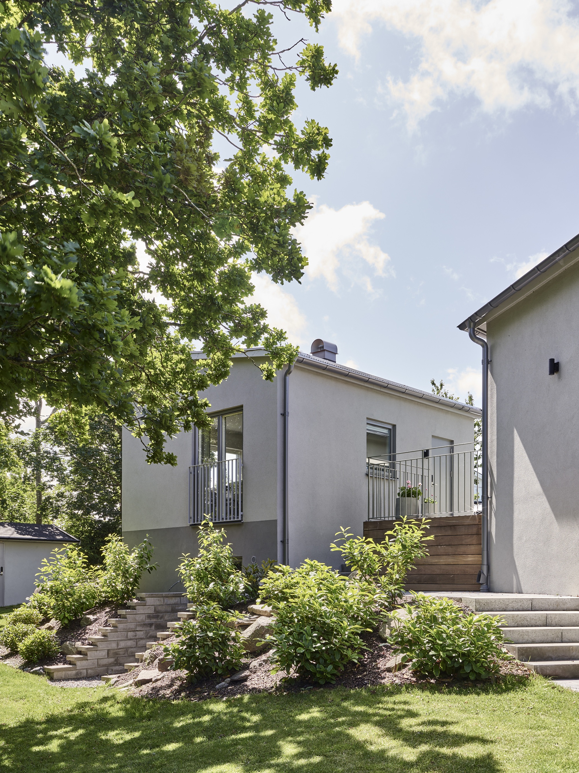 Dast stenhus putsade fasader i samspel med trädgård och grönska