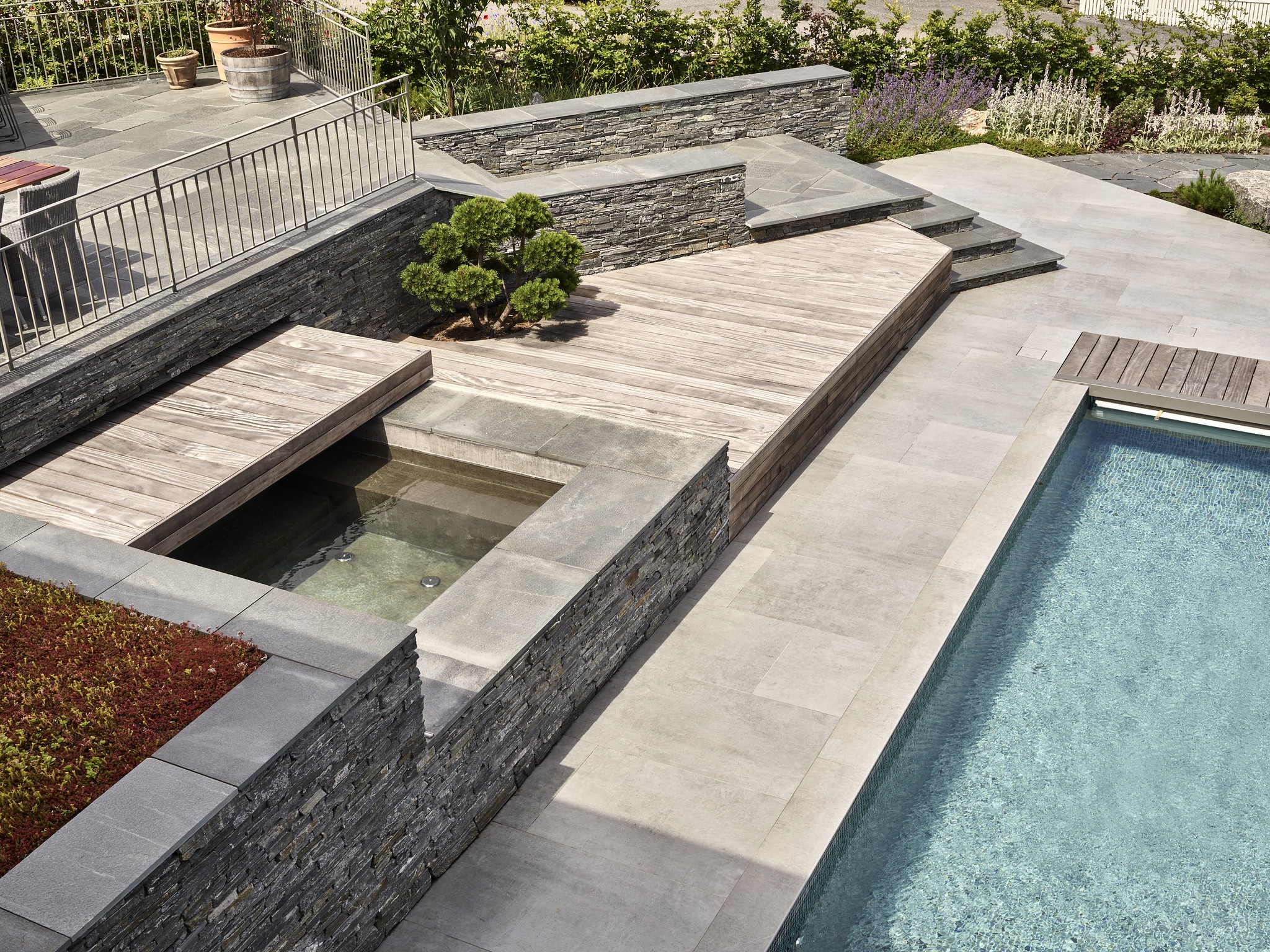 I dast stenhus koncept formar vi även trädgården - här en stenlagd utemiljö med pool och spa