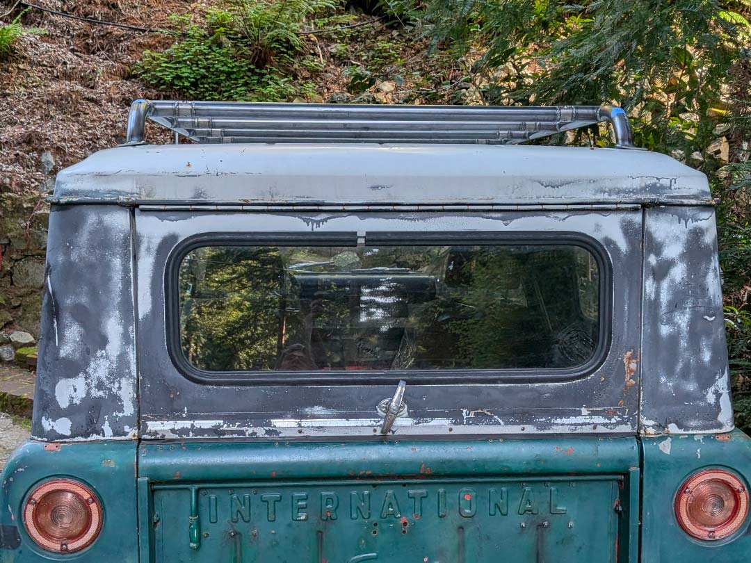 Scout II with off-road tires parked in a lot near buildings and trees.