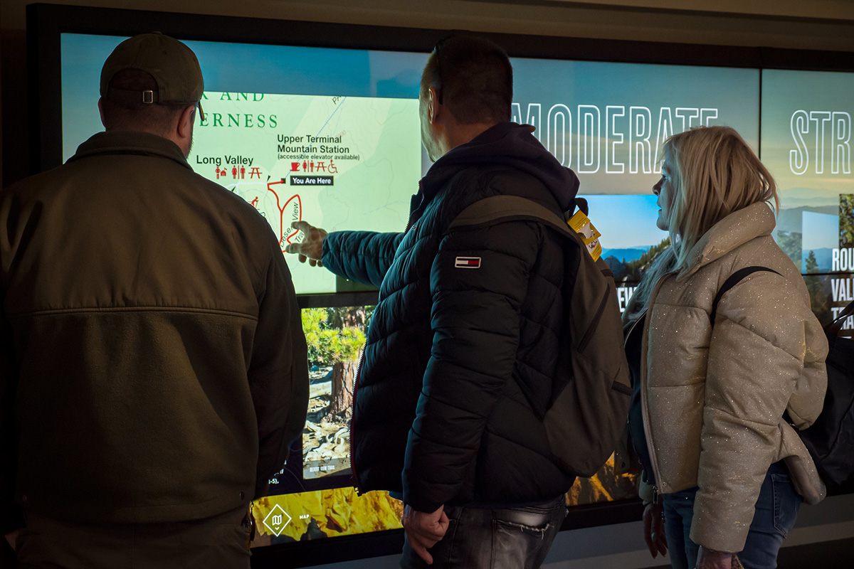 Visitors at the Palm Springs Aerial Tramway Mountain Station connect through shared discovery, tracing mountain trails side by side on Ideum’s immersive interactive video wall.