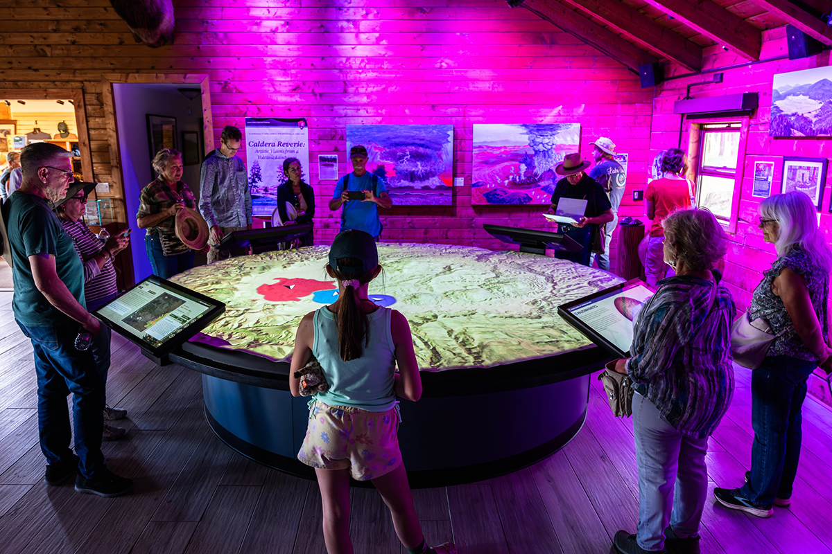 Visitors interact with the projection map table at the Valles Caldera National Preserve during the grand opening event.