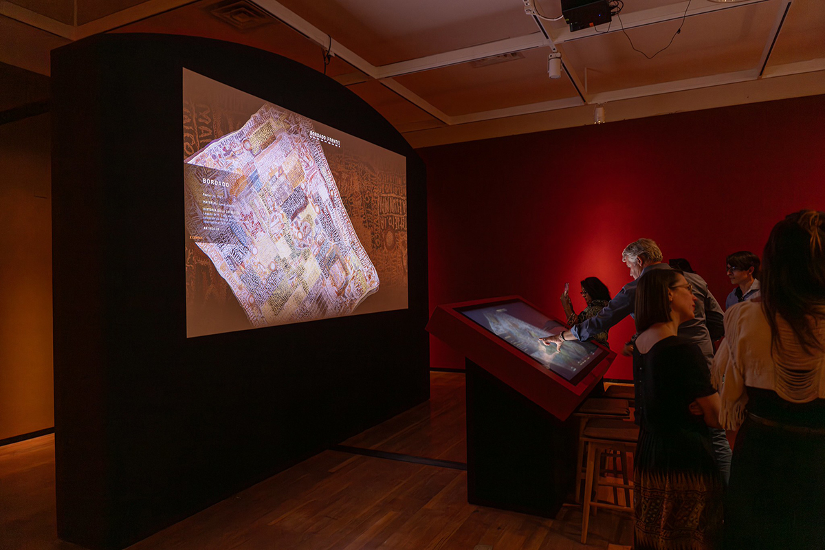 Visitors interact with the textile viewer at the grand opening for Appearances Deceive at the Museum of International Folk Art.