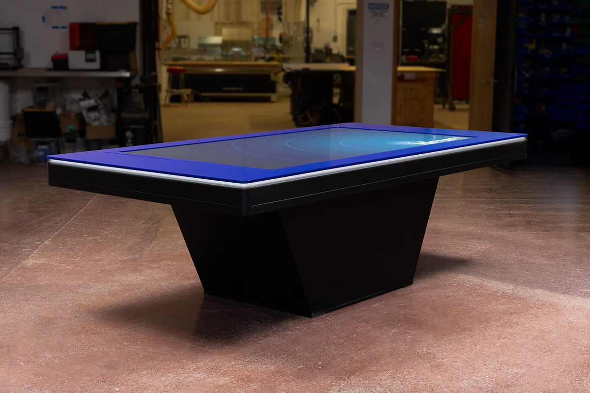 A fully custom 86” touch table, built of painted wood with a powder-coated aluminum top and LED lighting around the edge.