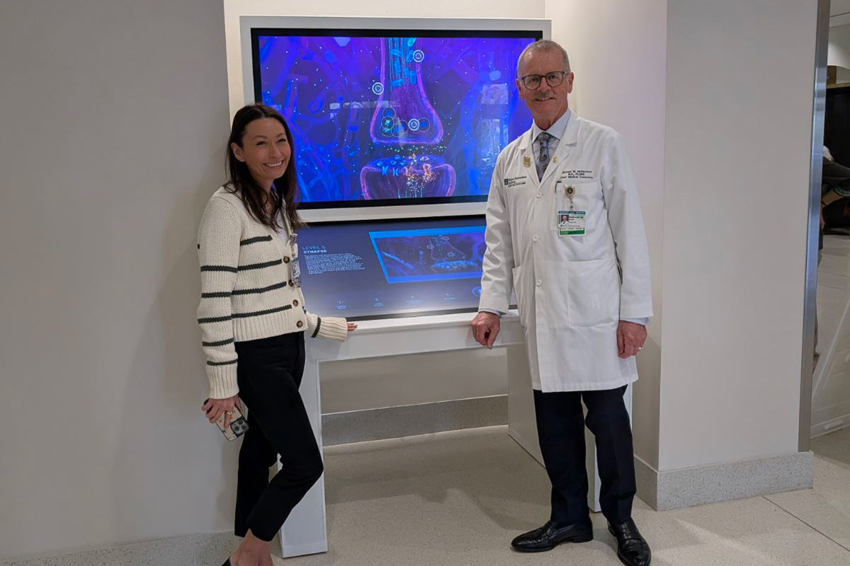 Michael McDermott, MD (right), chief medical executive of Baptist Health Miami Neuroscience Institute, poses with the newly installed interactive exhibit.