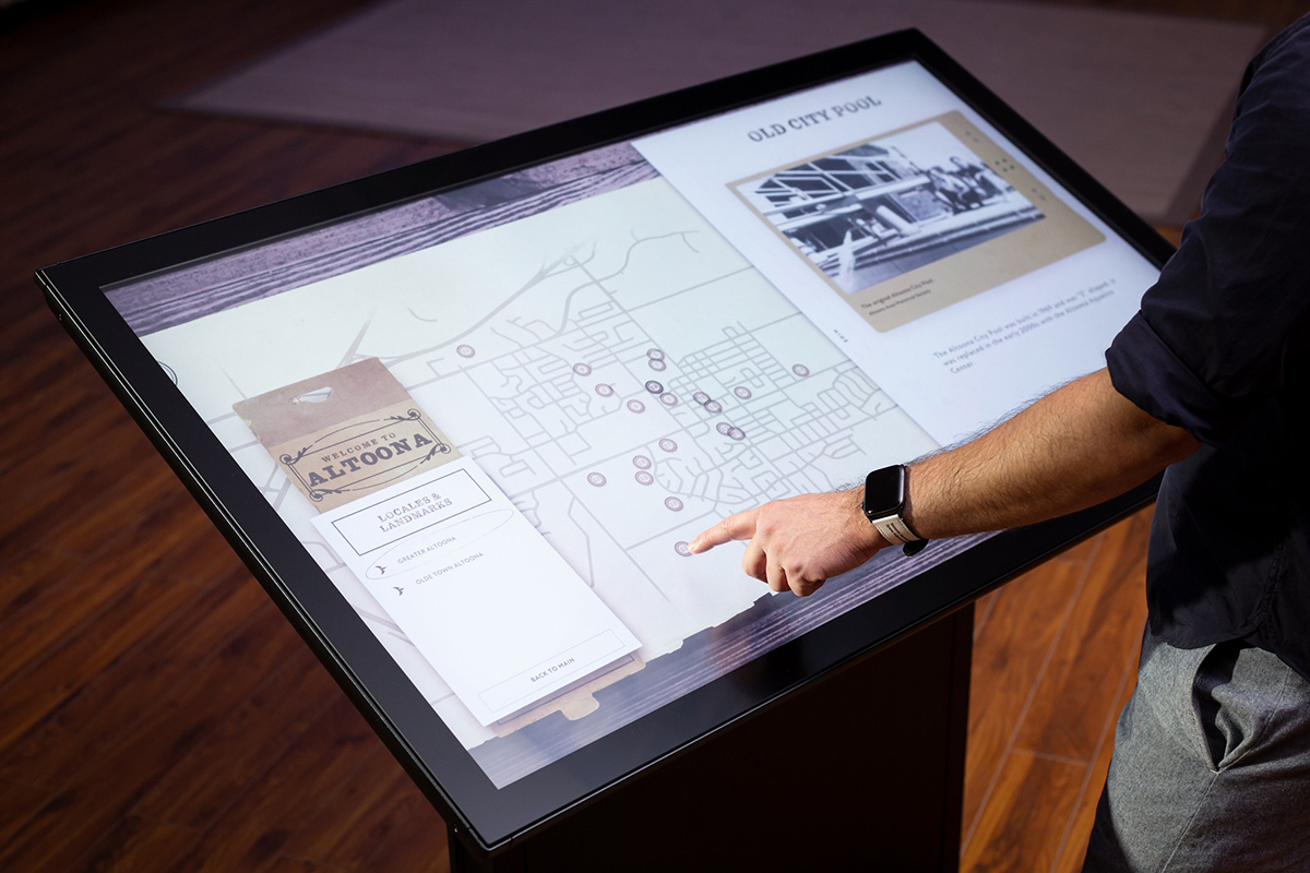 A user interacts with custom city informational software on a Drafting II touch table.
