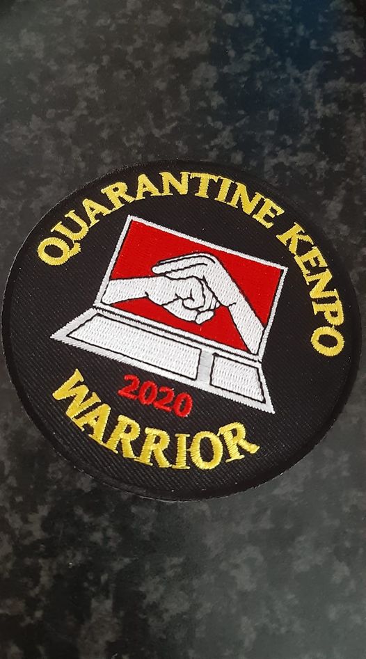 A kenpo patch design in black, white, red and yellow for quarantine kenpo. The center of the patch shows an open laptop screen showing hands on screen in peace over power salutation position. Around the laptop reads "Quarantine Kenpo Warrior 2020"