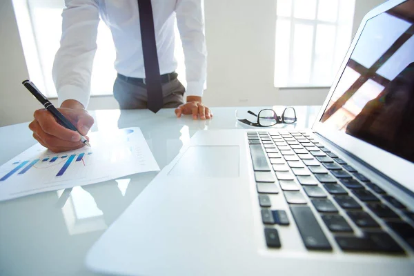 Consultant reviewing business charts beside a laptop