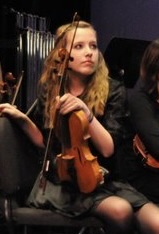 Claire as a teen holding a violin.