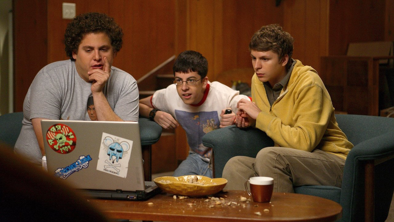 Movie still from Superbad. Three teen boys sit in a basement looking at a laptop.