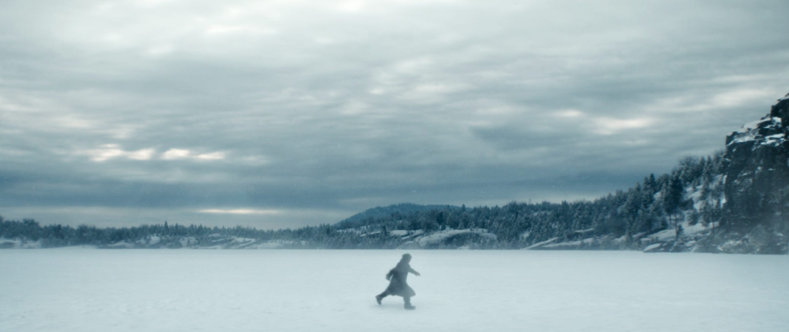 TV still from Severance. A person runs across a vast snowy landscape