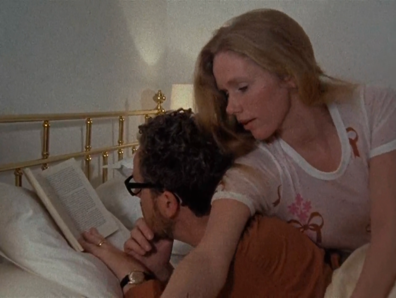TV still from Scenes From A Marriage. A married couple lie in bed, the man reading a book.