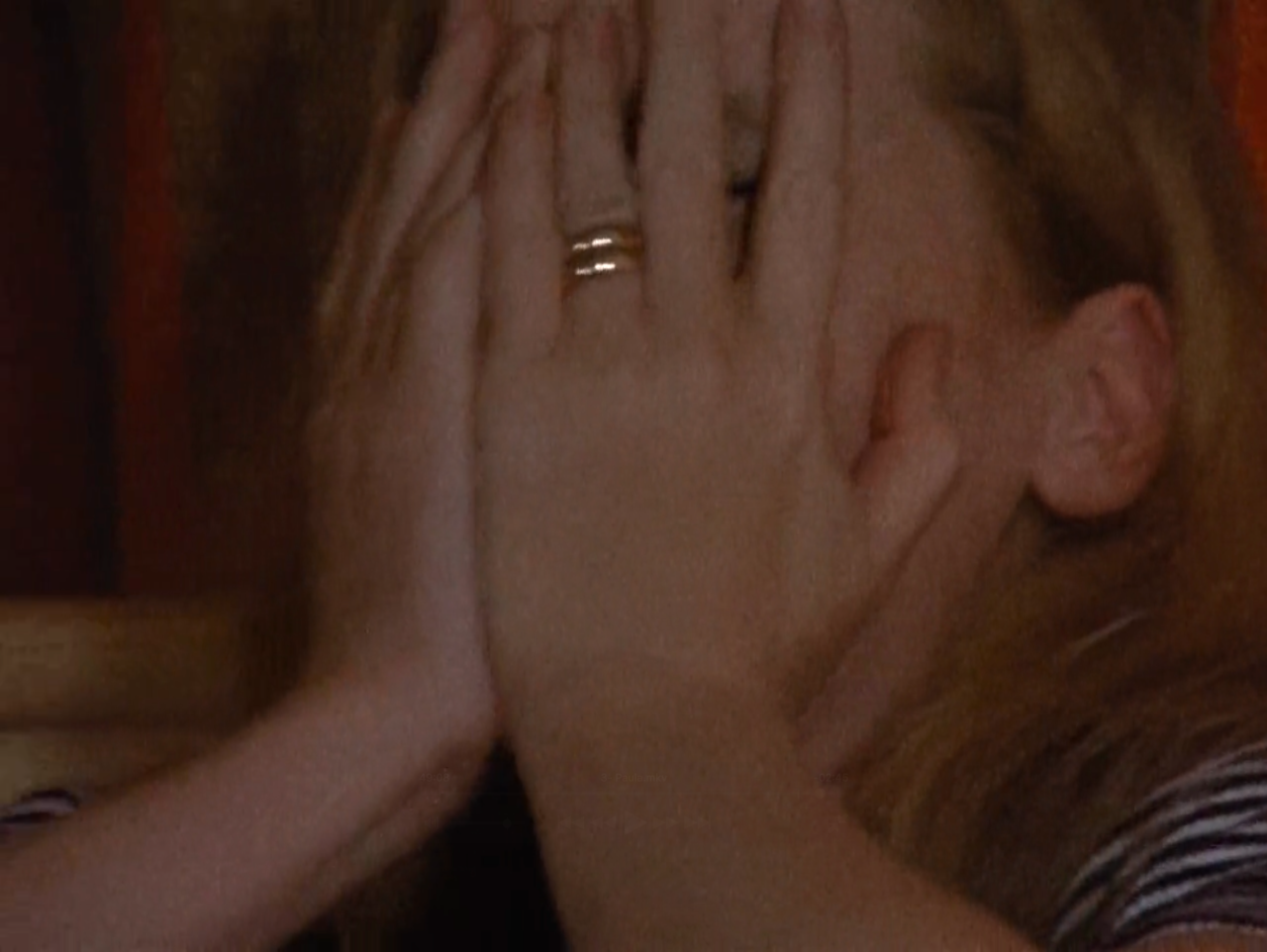 TV still from Scenes From A Marriage. A woman cries with her hands on her face, wedding band visible.