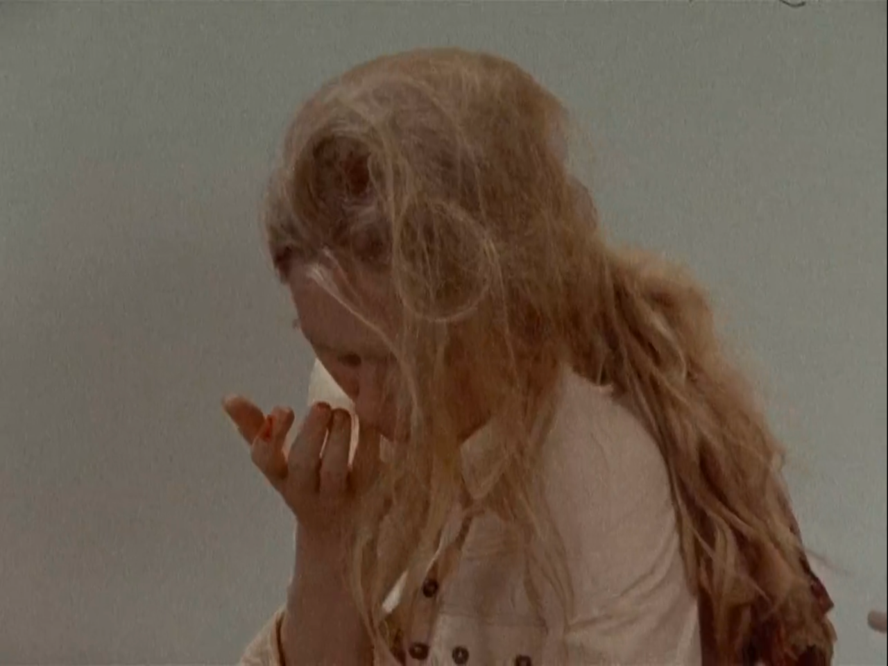 TV still from Scenes From A Marriage. A woman touches her face - her nose is bleeding from being hit.
