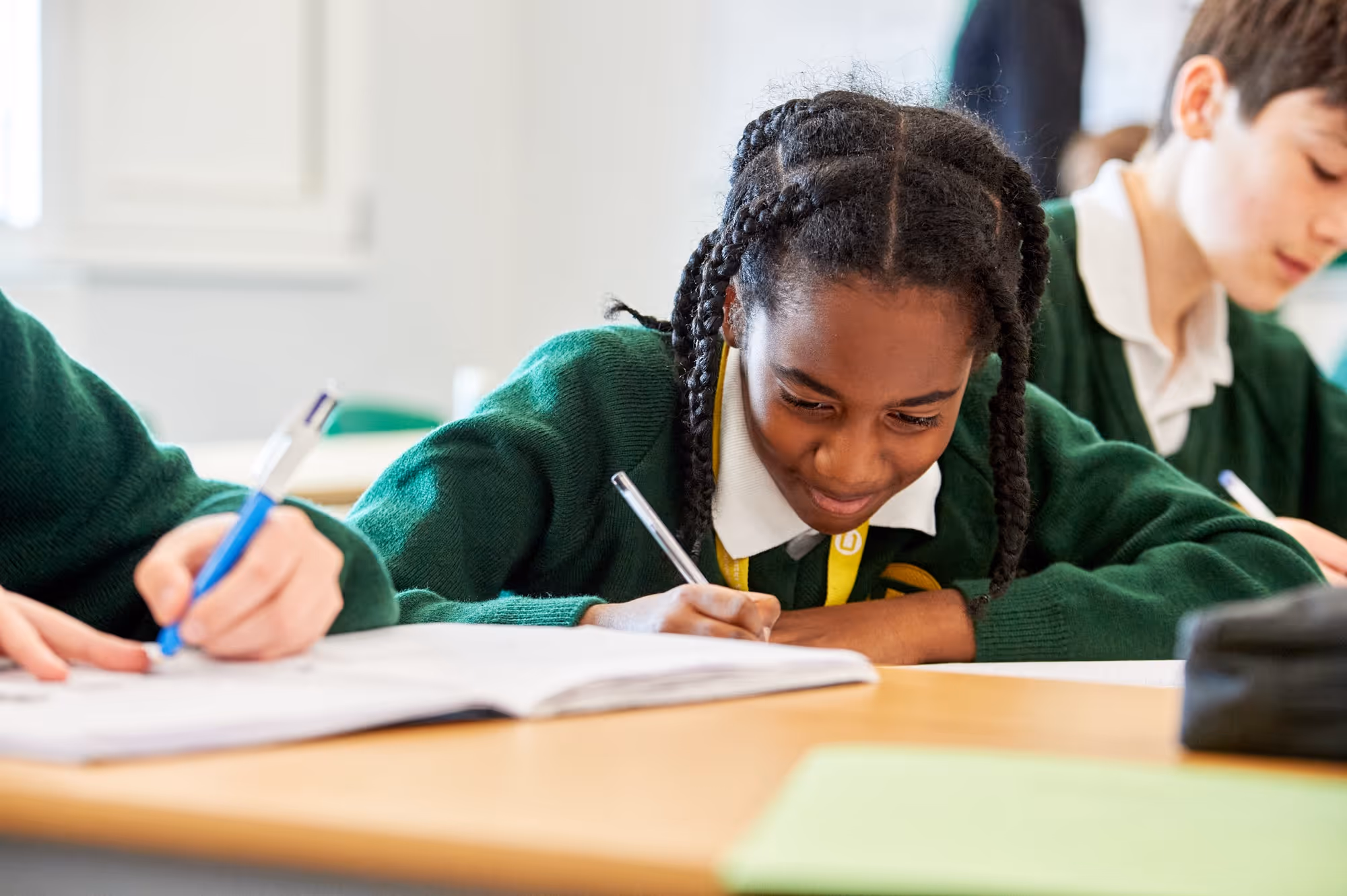 A student leaning over their book writing during a lesson