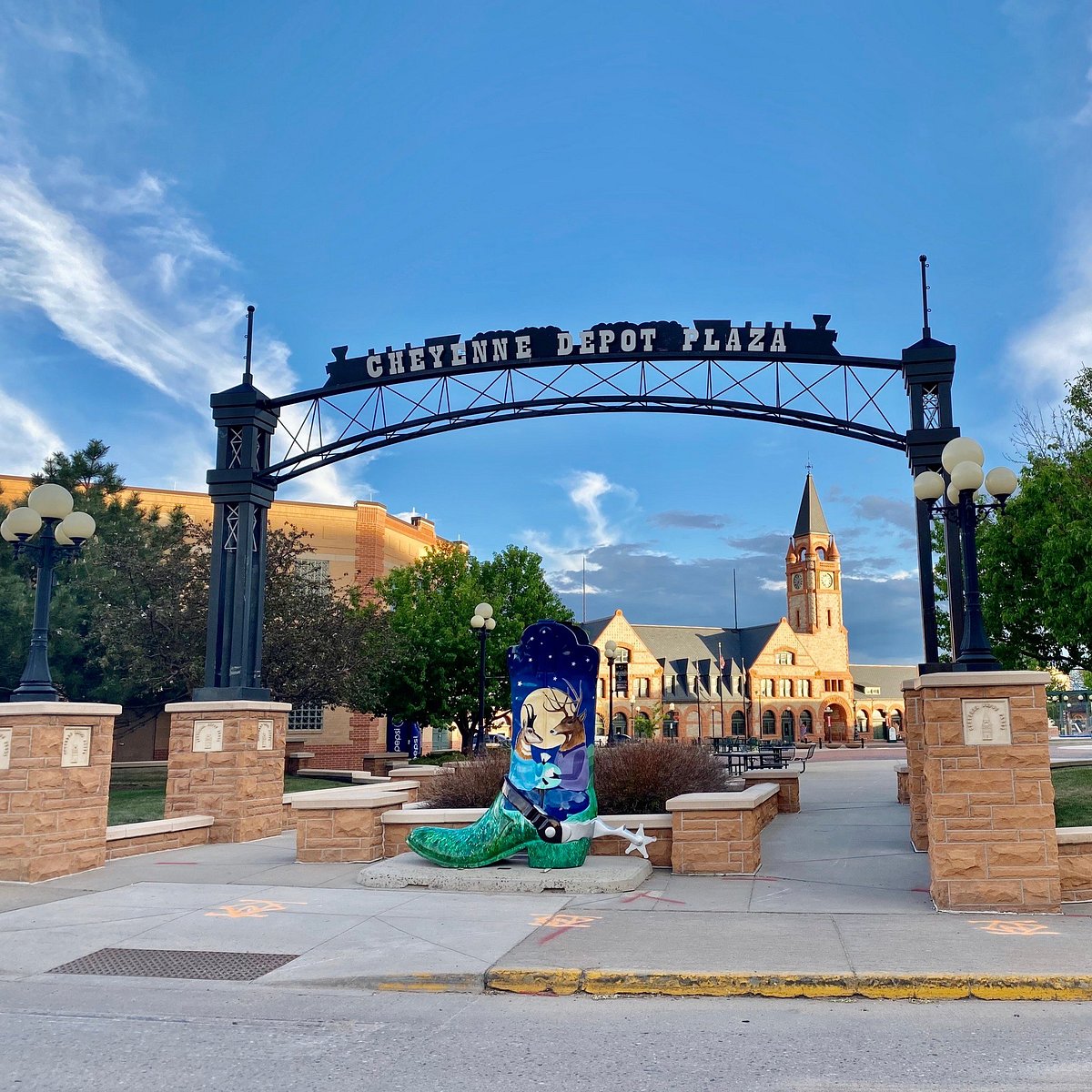 Cheyenne Depot Plaza archway over sidewalk with a large decorative cowboy boot sculpture and historic brick clock tower building in the background.