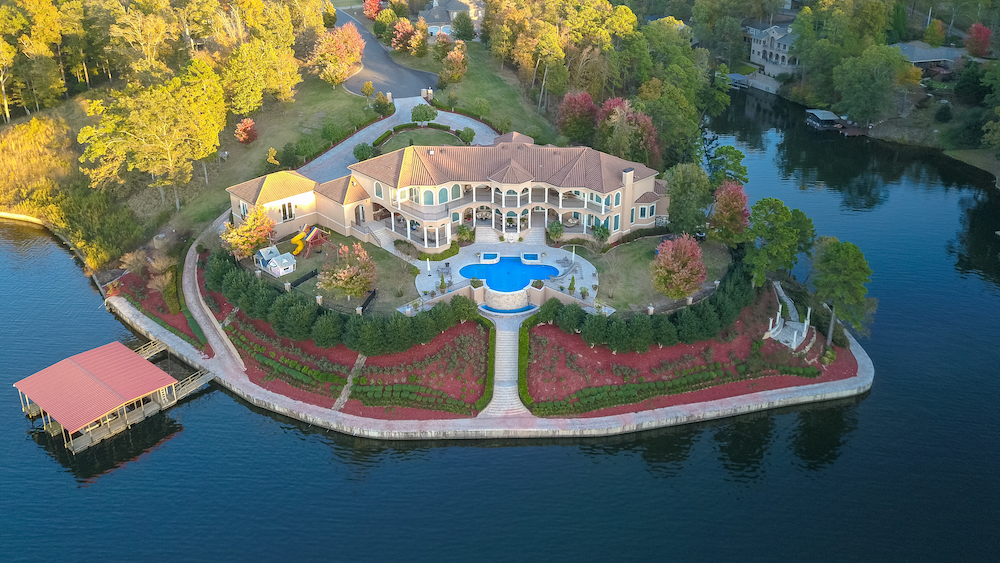 Drone view of a waterfront estate with a swimming pool and landscaped shoreline