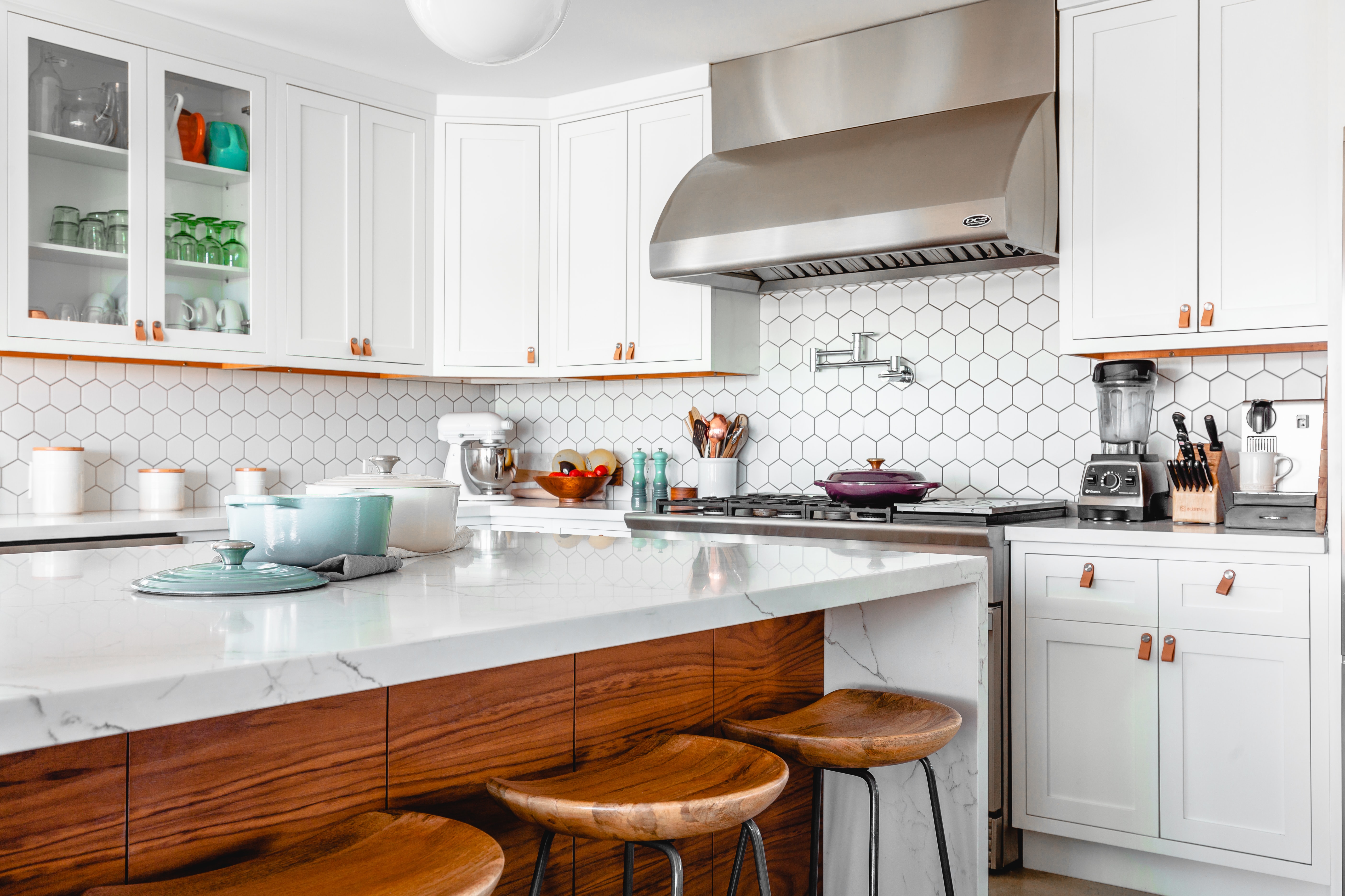 Bright white kitchen with a wood island, marble countertop and stainless steel range
