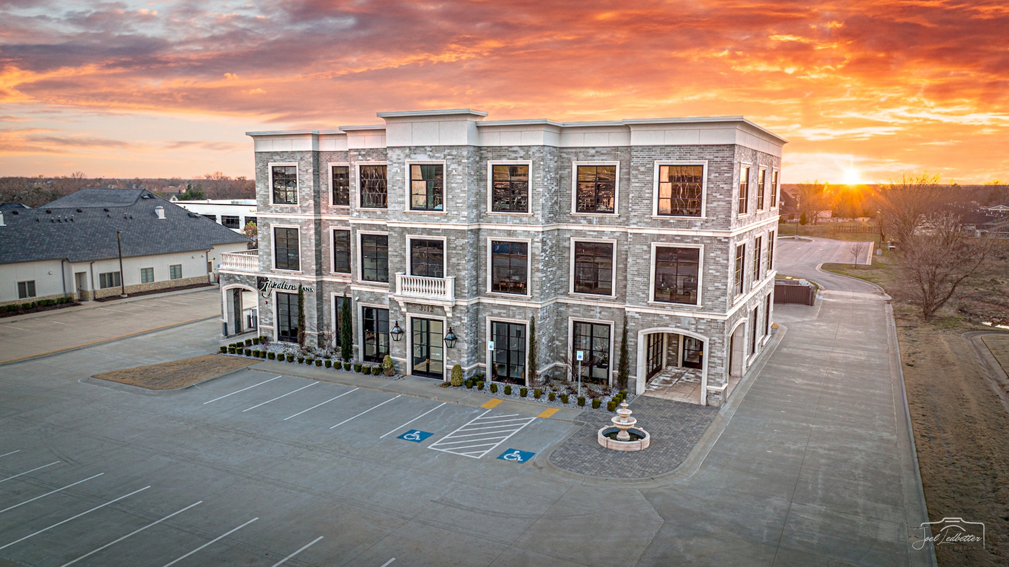 Signature Bank building and parking area photographed from above at sunset