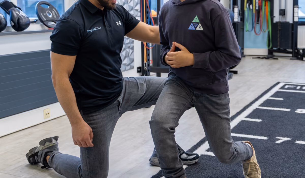 Fysiotherapeut begeleidt een kind tijdens een functionele knie- en stabiliteitsoefening in de trainingsruimte van PhysiqCare.