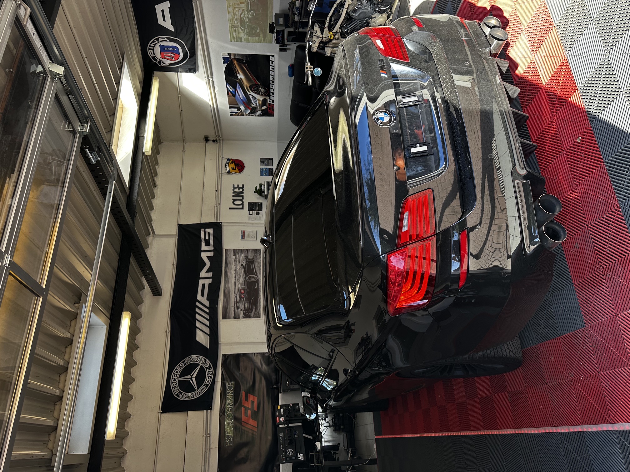 Heckansicht eines schwarzen BMW M-Modells mit FS Performance Kennzeichen in der Werkstatt-Lounge in Hamburg