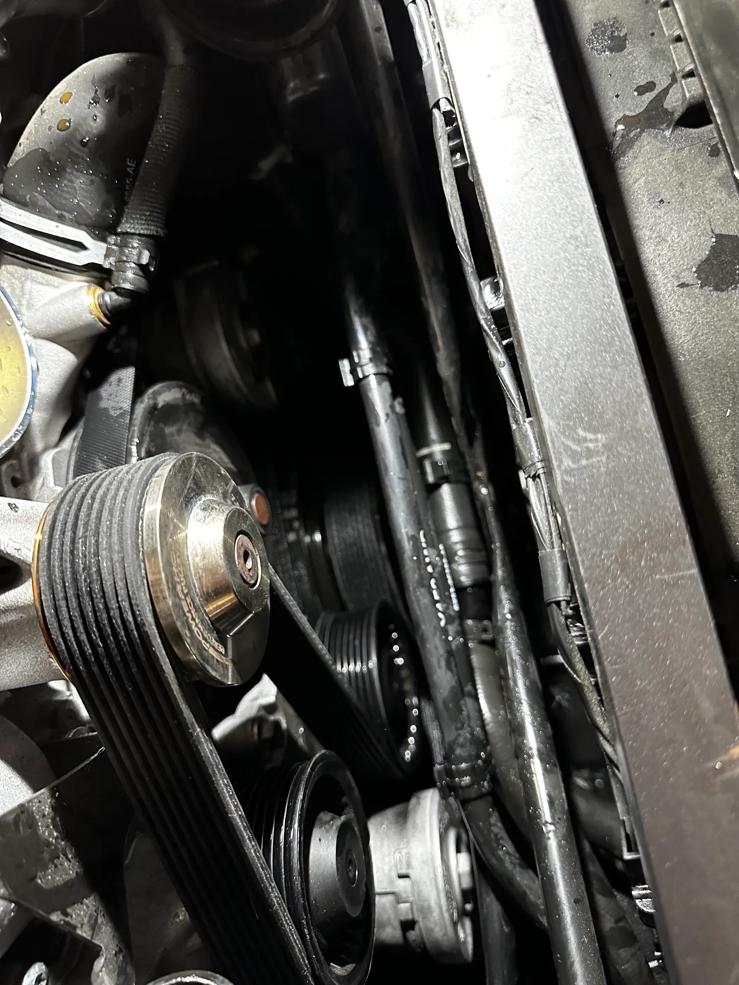 Detailaufnahme im Motorraum des Jaguar F-Type SVR mit Kompressor während des Pulley-Tausches bei FS Performance in Hamburg