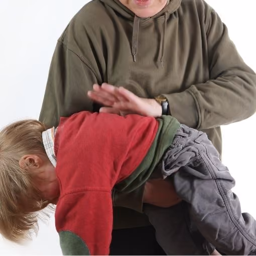 Adult wearing a green hoodie holding a child bent over, about to give a spanking.