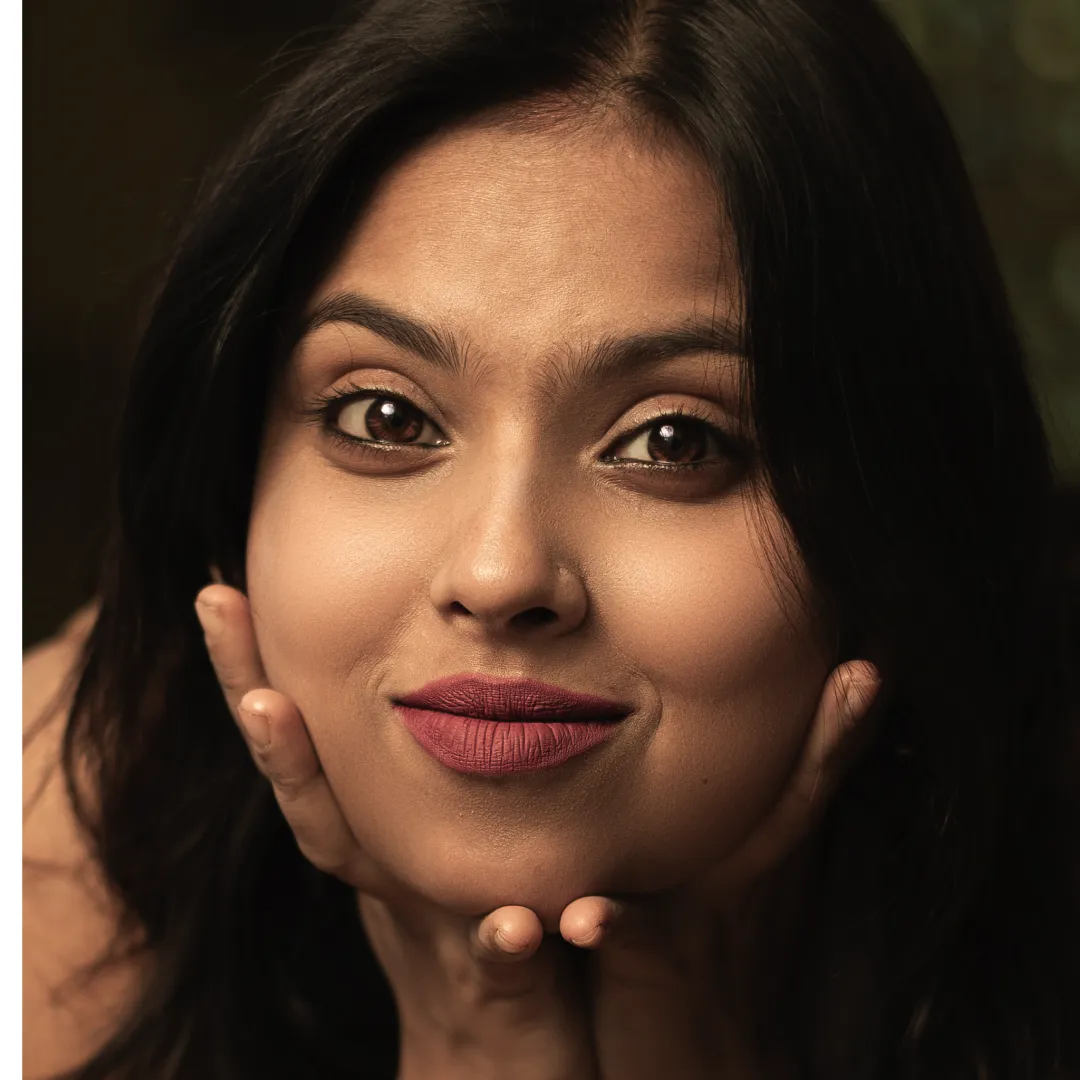 Young adult woman with long dark hair posing with hands near the face.