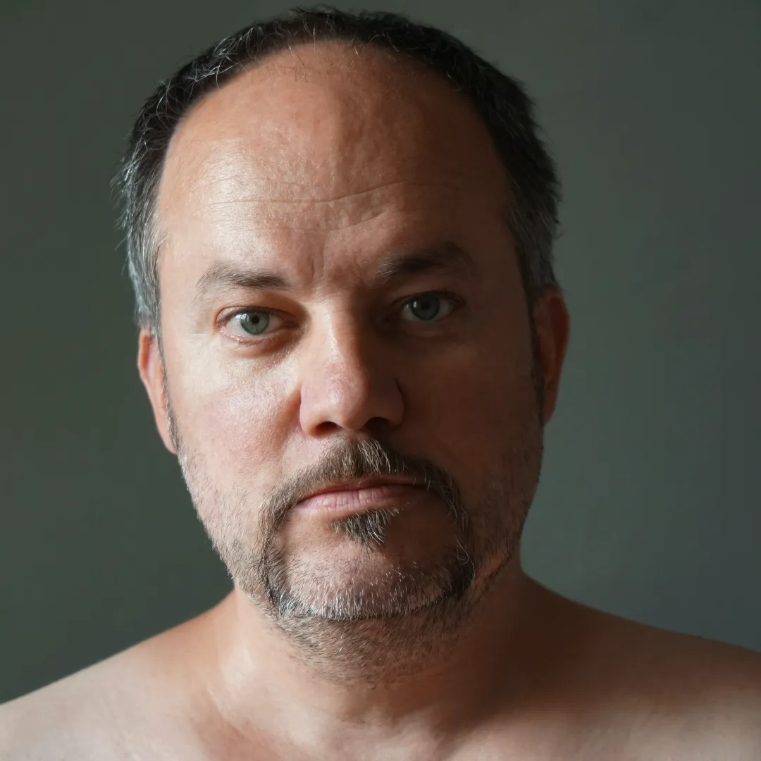 Portrait of a middle-aged man with short gray hair against a neutral background.