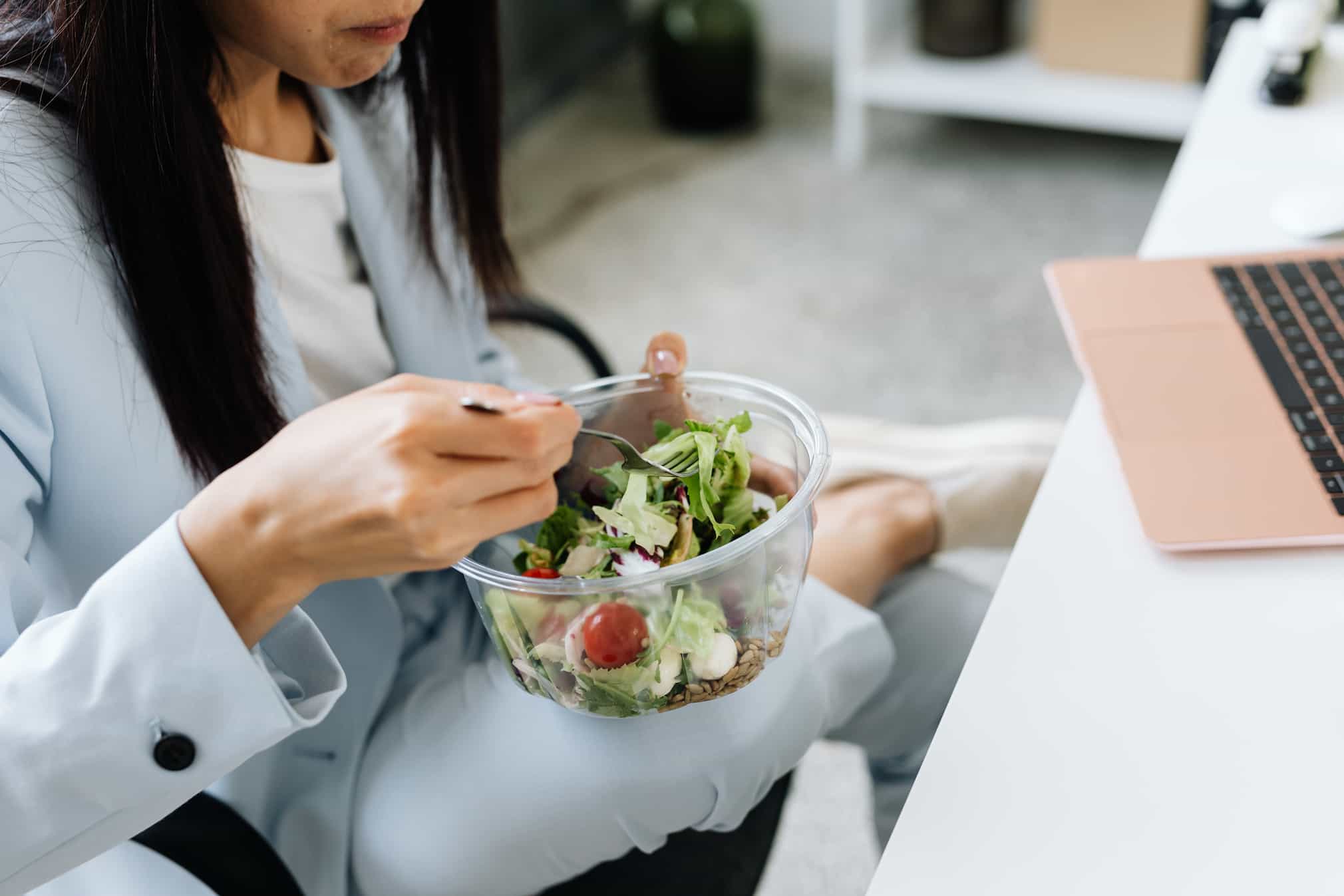 An image of a woman eating salad