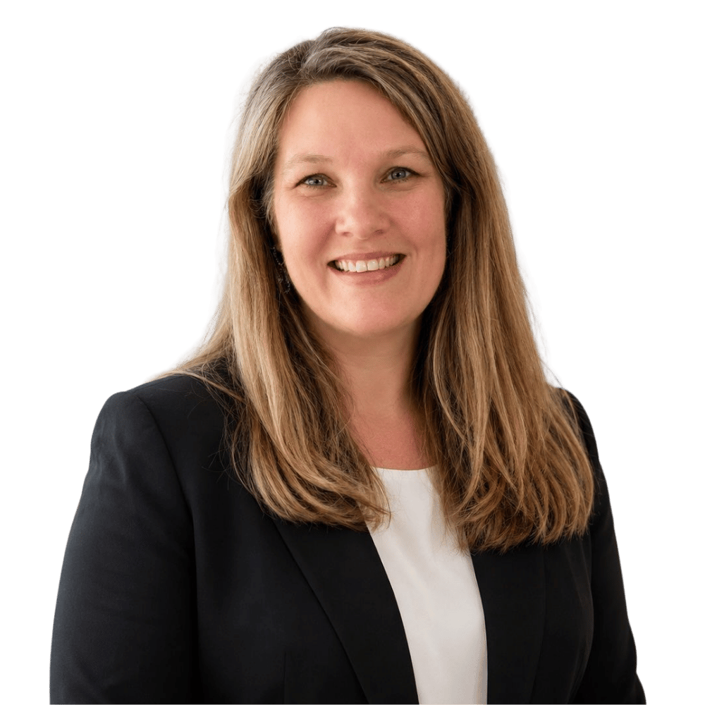 Smiling audiologist with blonde hair wearing a colorful floral dress and a necklace.