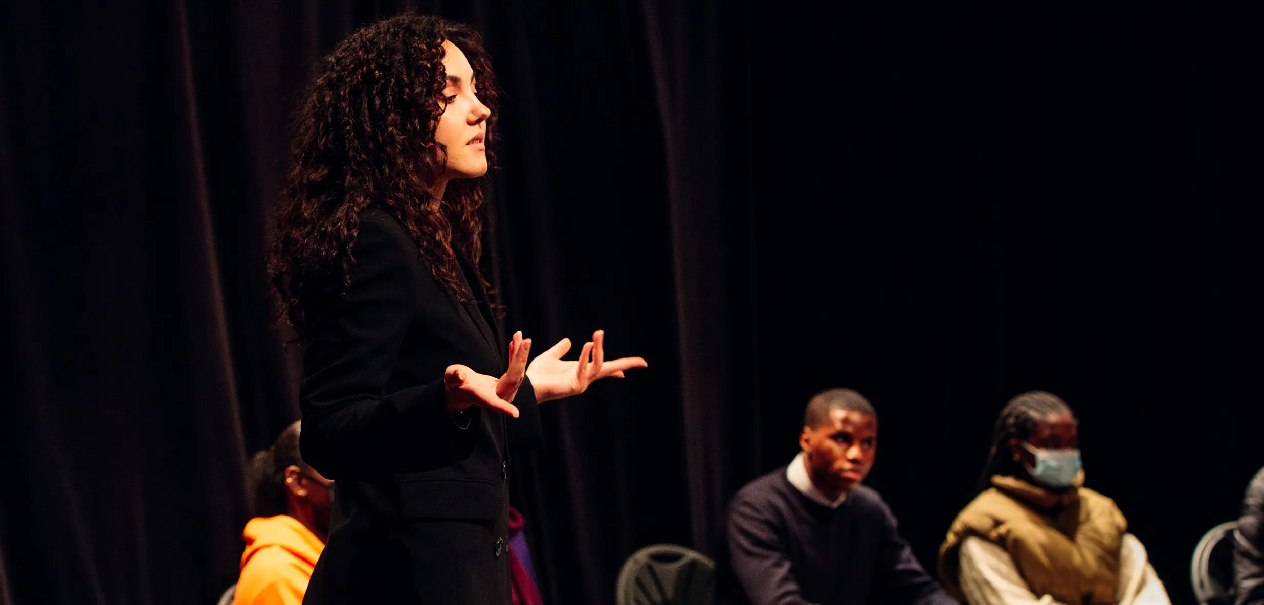 Femme parle en public avec ses gestes devant un auditoire
