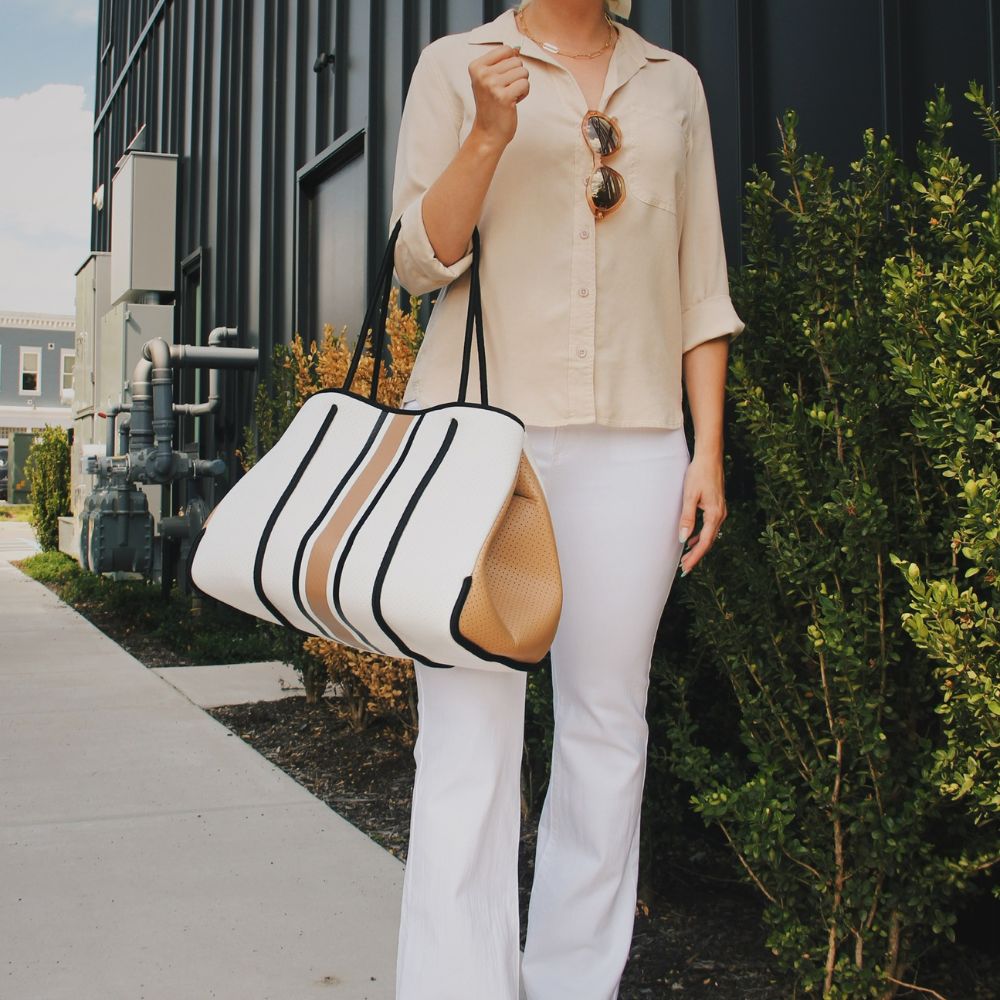 Stylish beige shirt with white pants and a brown and white duffle bag