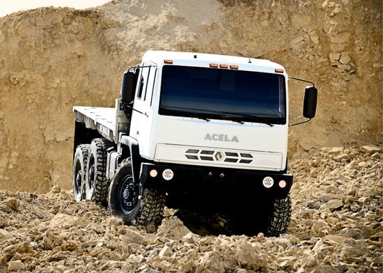 Acela Monterra 6x6 with flatbed driving through uneven terrain at a Canadian mining site, showcasing off-road capability