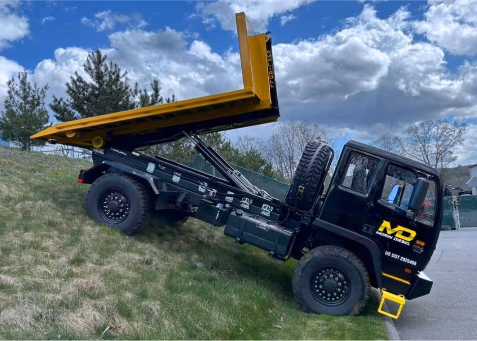 Acela Monterra 4x4 with flatbed hooklift extended on a hillside, demonstrating off-road stability.