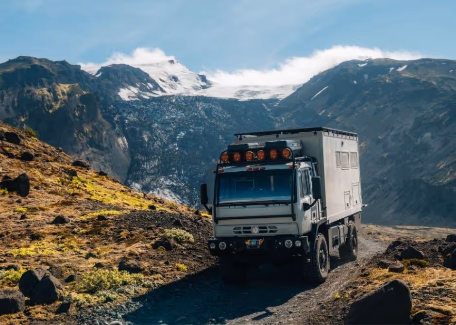 4xploration’s Acela Monterra 4x4 with overlanding habitat box cresting a hill during an Iceland expedition, with a glacier in the background