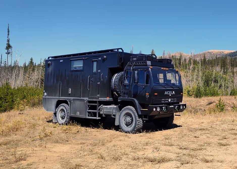 Black Acela Monterra 4x4 with overland body designed by Intercontinental Truck Body Alberta, parked at a campsite