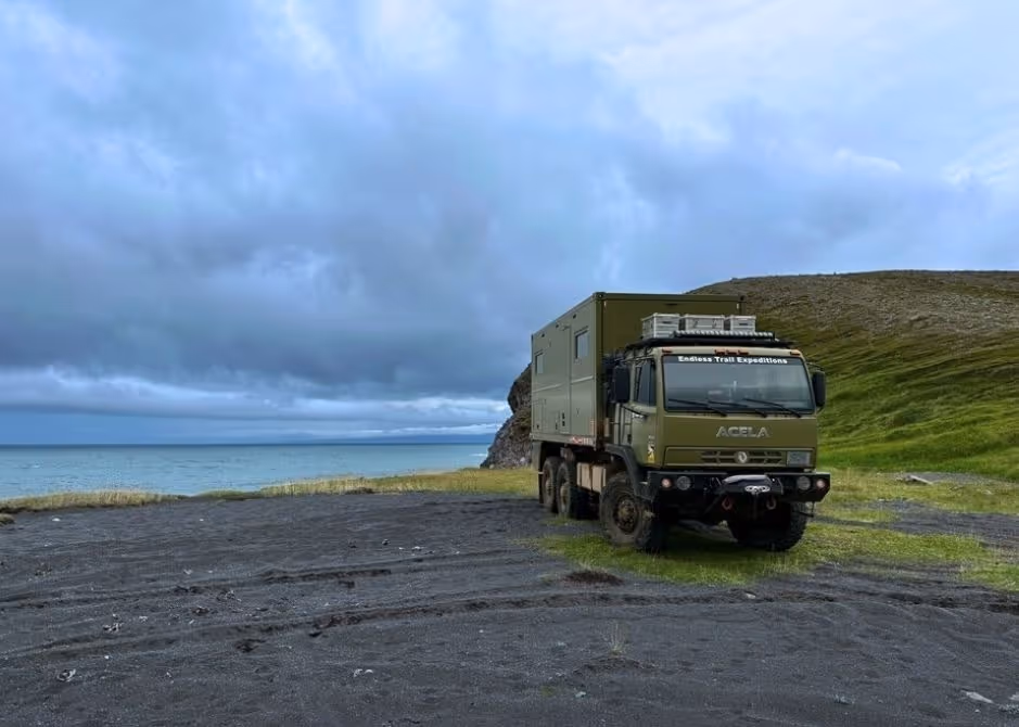 BAT, the Acela Monterra 6x6, parked on a black sand beach in Iceland during an overland expedition