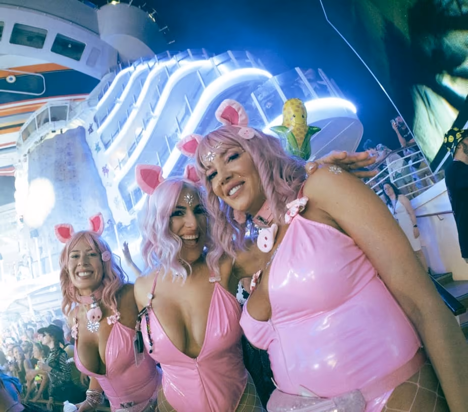 Group of women wearing pink festival costumes enjoying a late-night set under full production lighting on rave cruise
