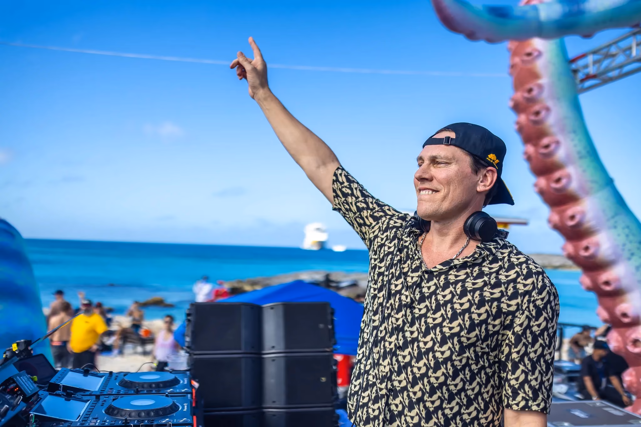 Tiësto performing at Groove Cruise 2024 on Great Stirrup Cay beach with fans dancing in the sand