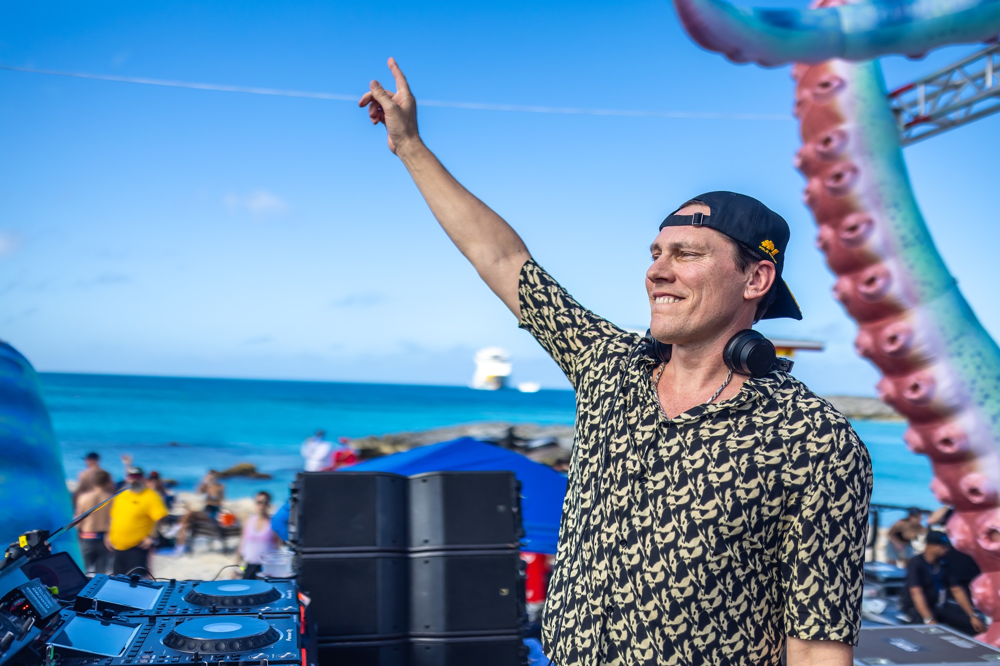 Tiësto performing at Groove Cruise 2024 on Great Stirrup Cay beach with fans dancing in the sand