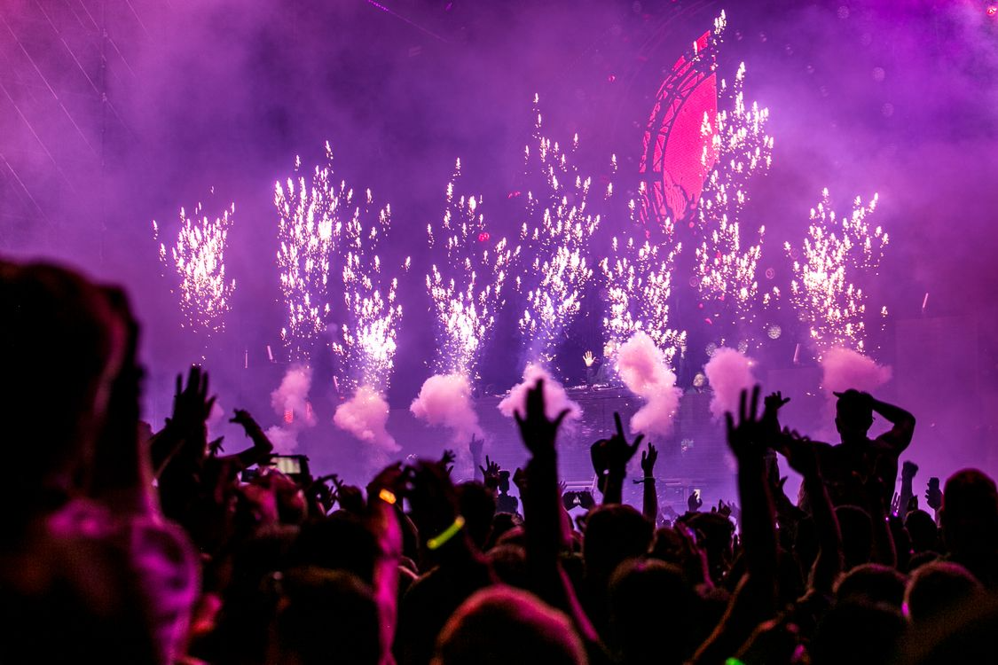 Crowd of excited festival goers at Ultra Music Festival Miami with pyrotechnics in the background