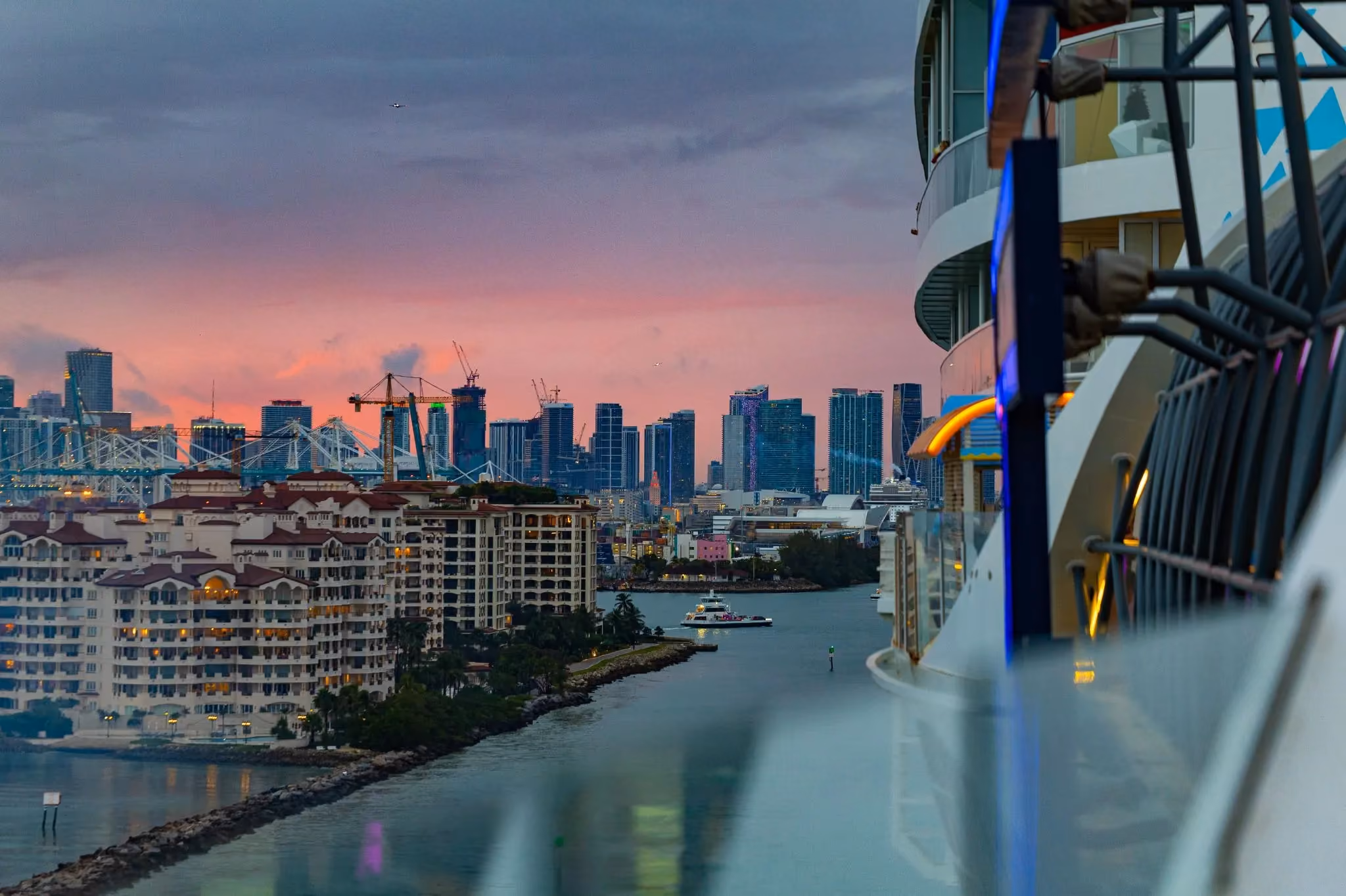EDM cruise ship sailing back into the port of Miami with the sunrise glow over the skyline.