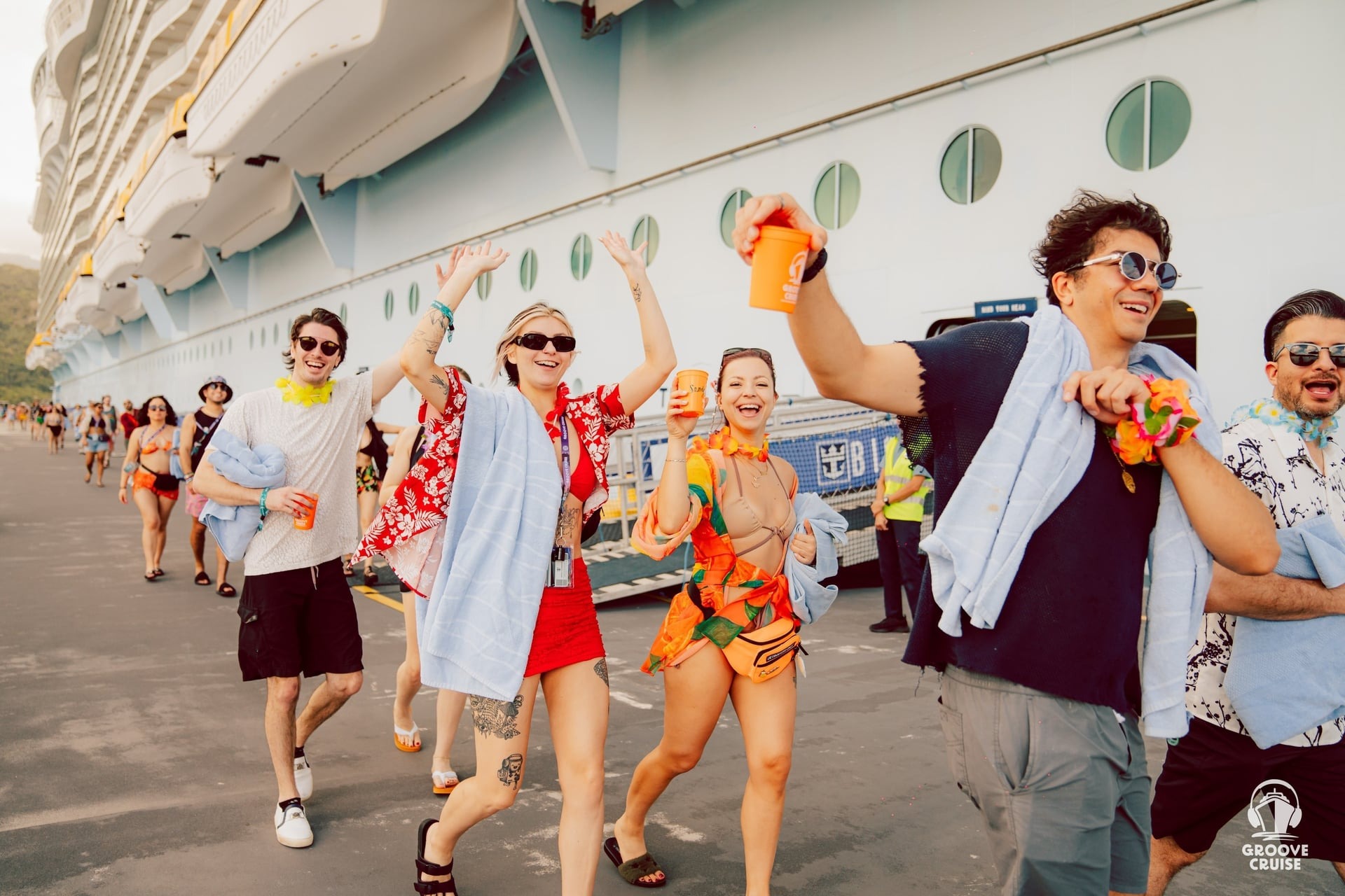 Excited EDM cruise festival attendees walking off the ship to a Caribbean destination stop