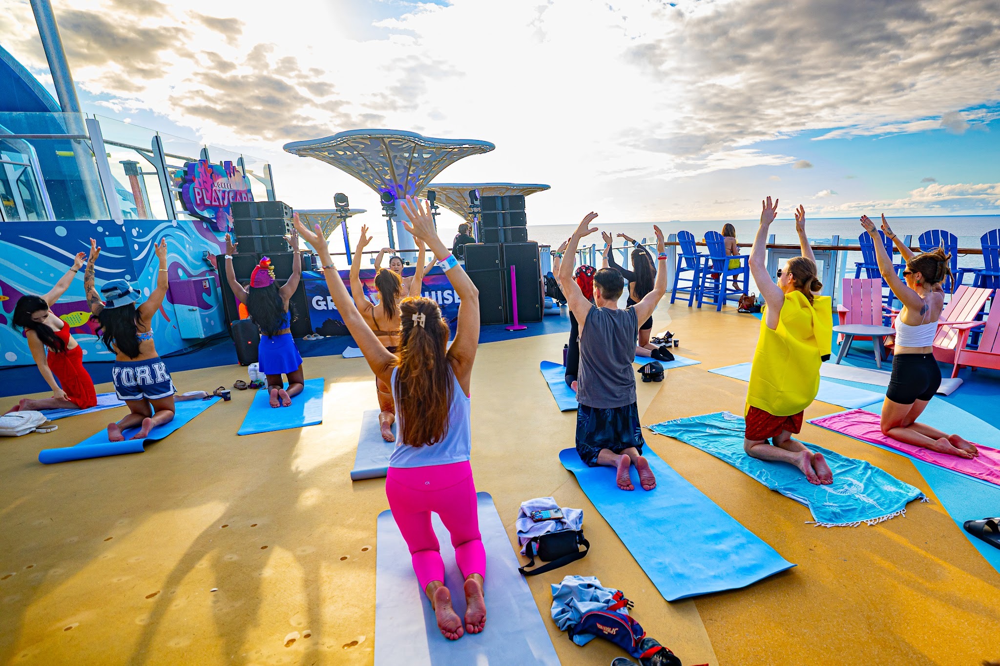 Music festival attendees participating in an outdoor yoga class aboard a rave cruise.