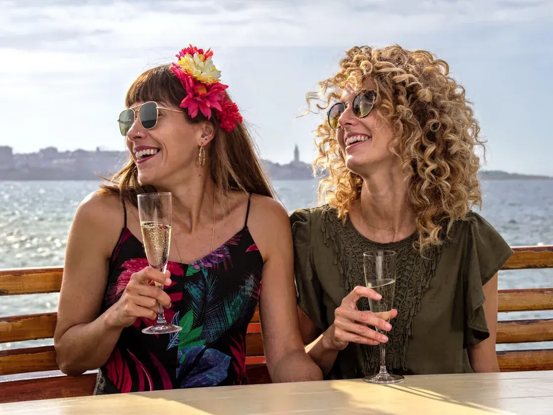 2 friends laughing on a boat by the sea