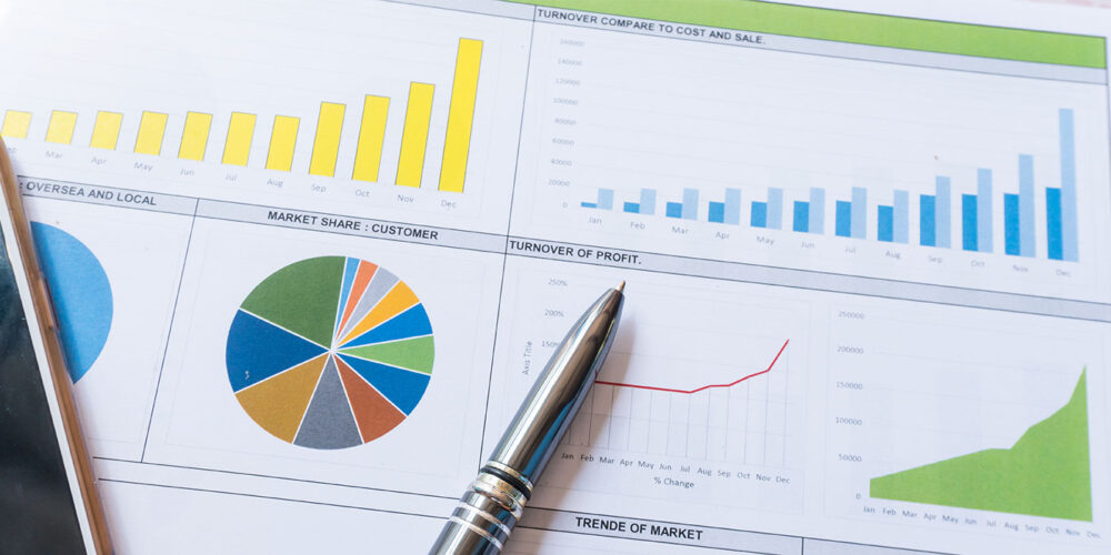 Graphs and charts displaying financial data analysis with a pen on a report sheet.