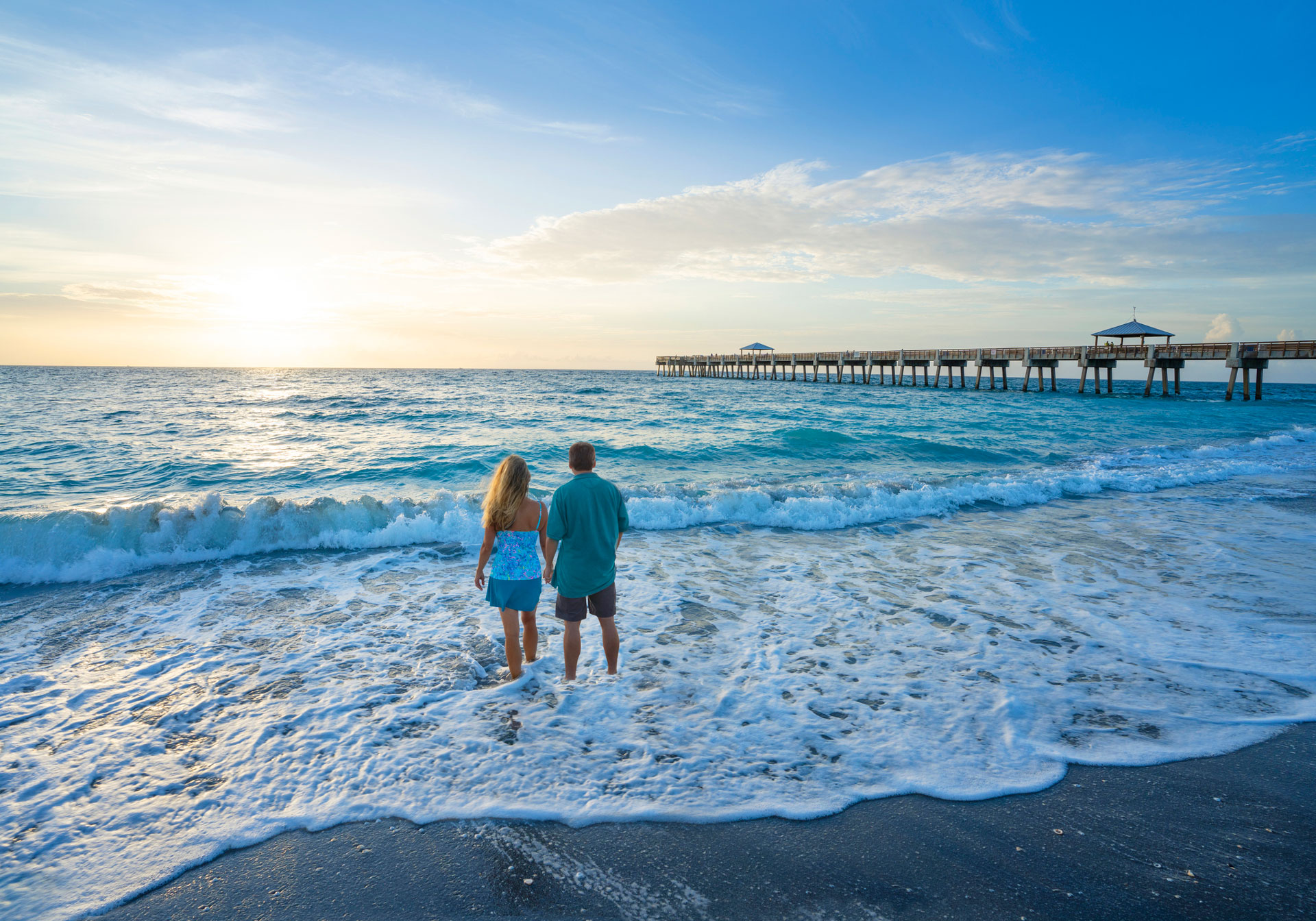 Portrait of a couple standing in the waves on a beach.